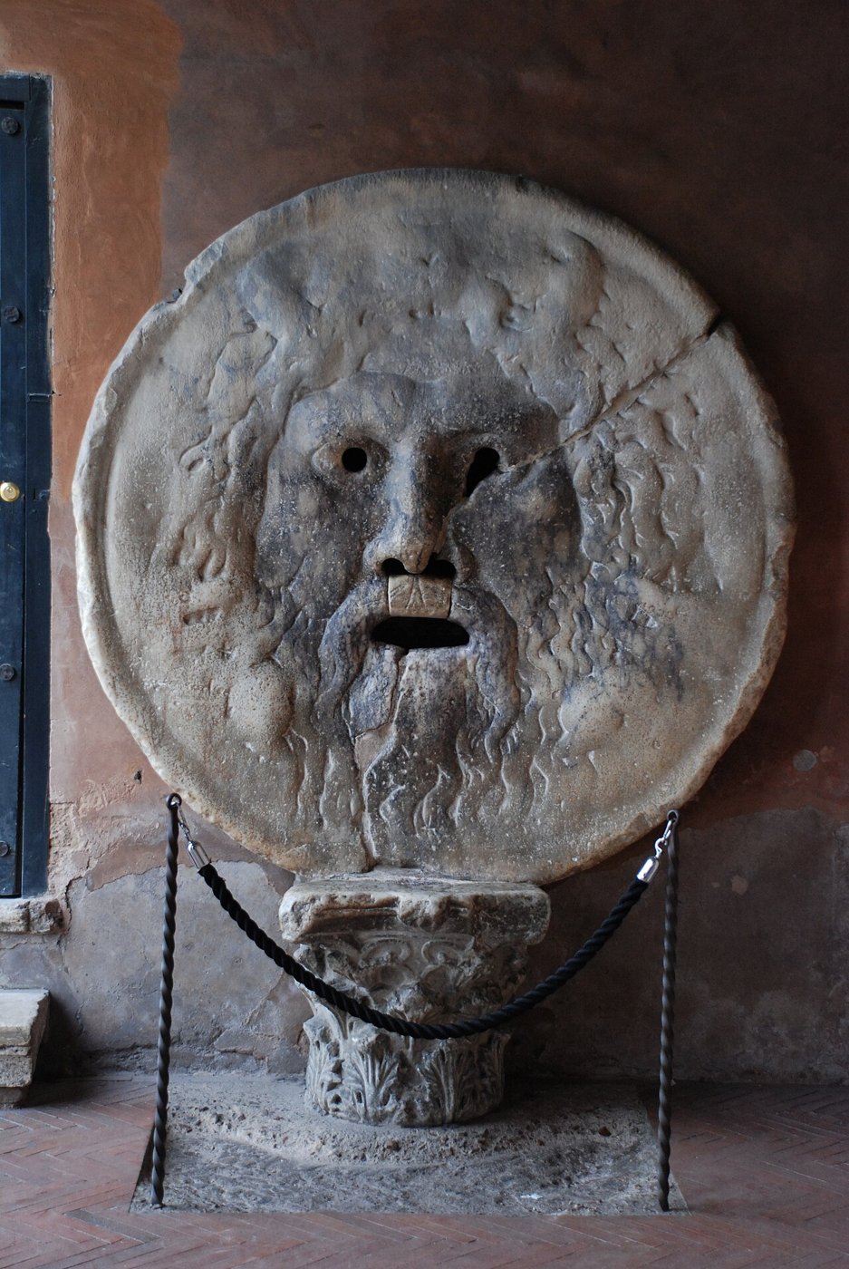 A Boca da Verdade, grande máscara de mármore com rosto barbado e boca aberta, no pórtico de Santa Maria in Cosmedin, em Roma