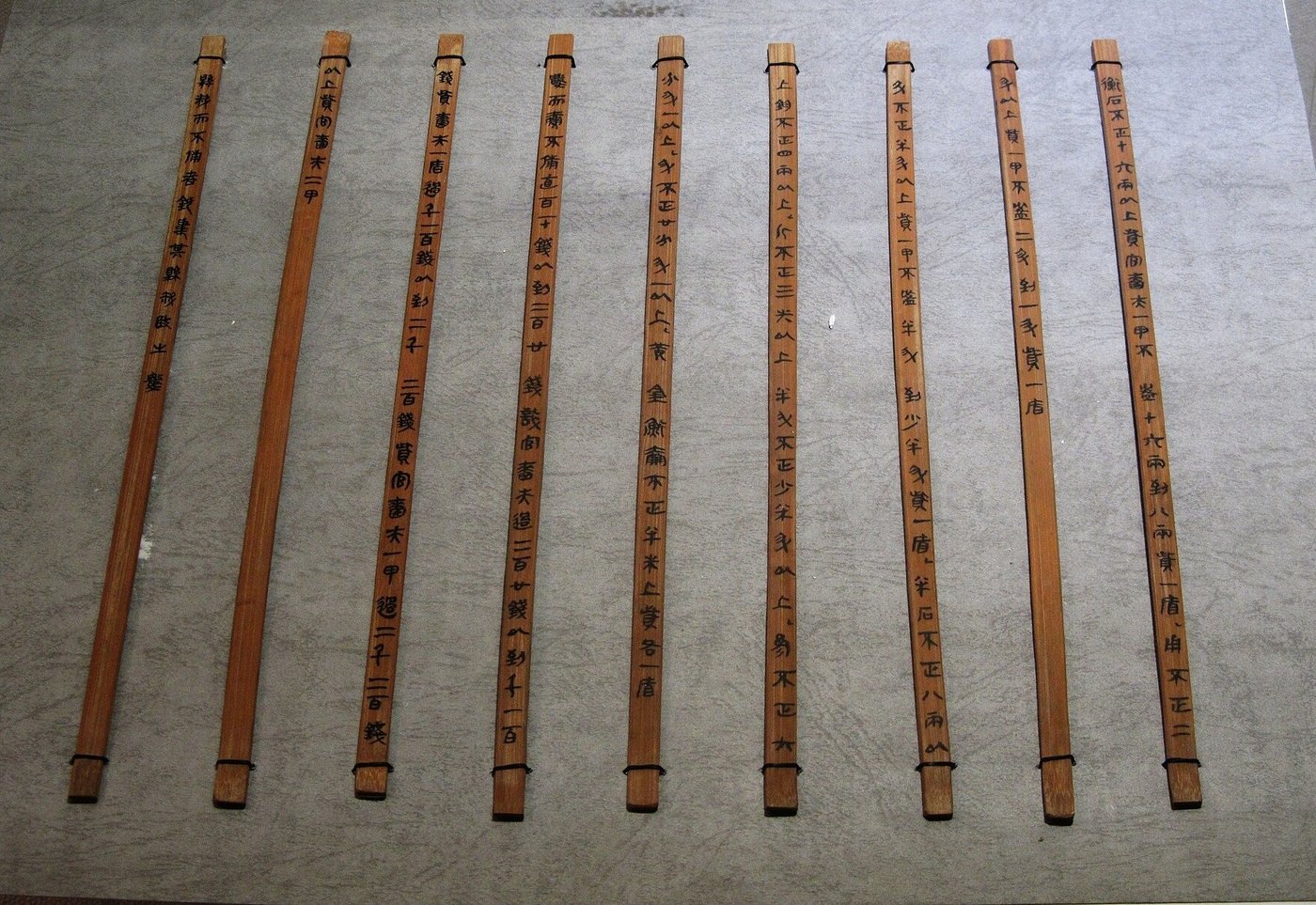 Tiras de bambu da dinastia Qin com textos legais, amarradas com fio