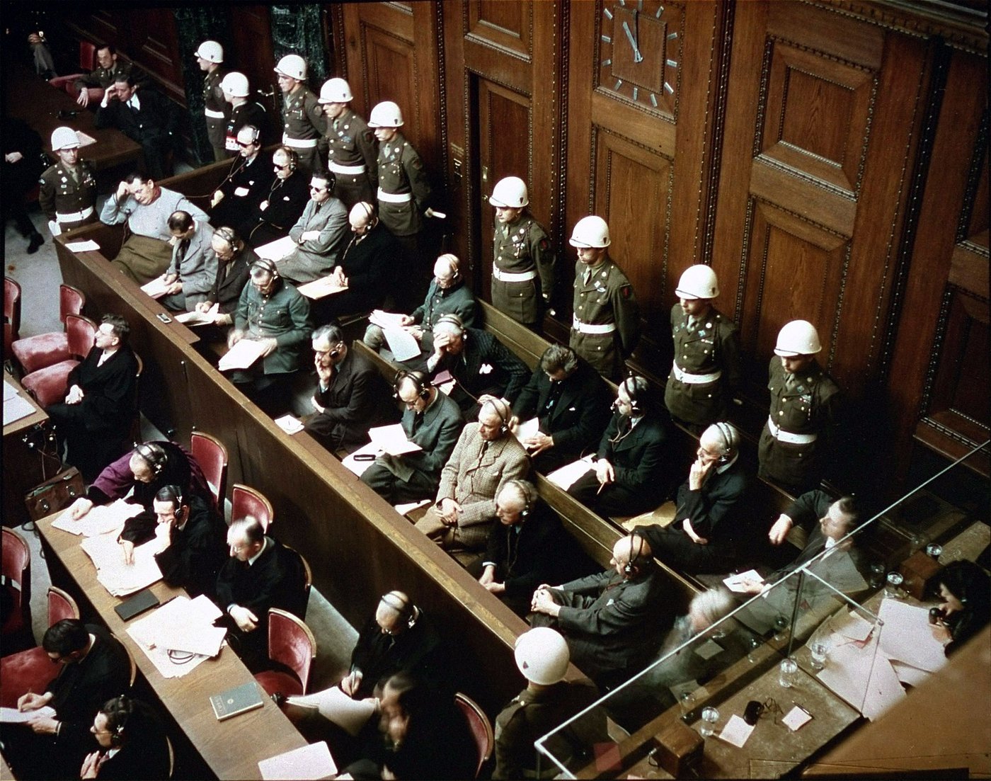 Os réus no banco dos acusados do Tribunal Militar Internacional de Nuremberg, guardados por soldados de capacete branco