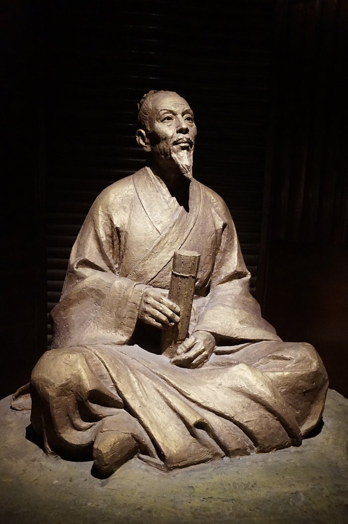 Estátua de Zu Chongzhi, sentado, segurando uma tira de bambu