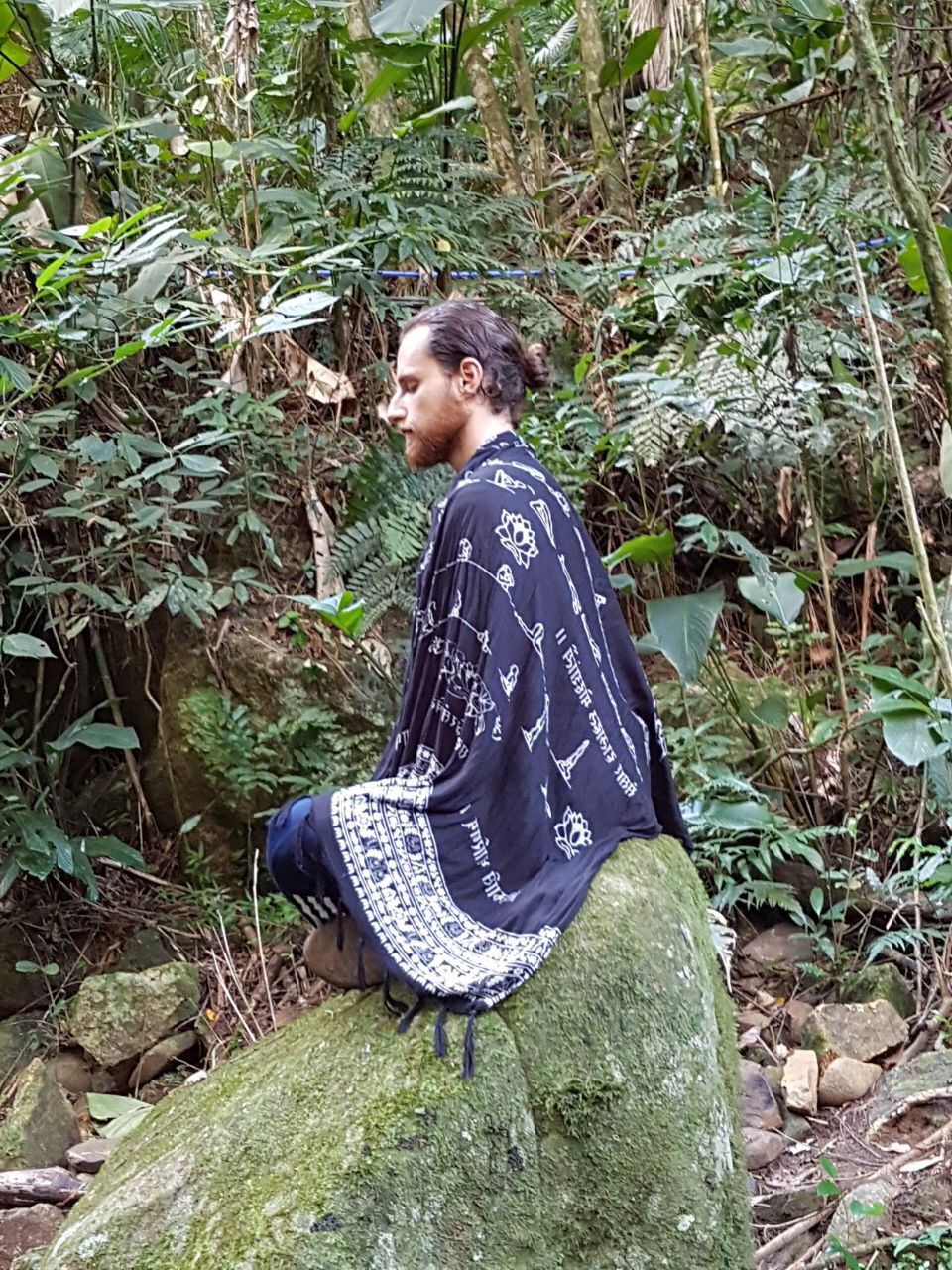 Lucas meditando sobre uma pedra na floresta